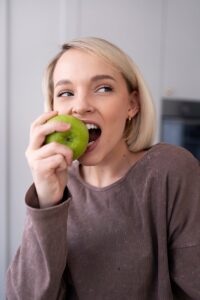 Woman eating healthy food to support teeth recovery and oral health