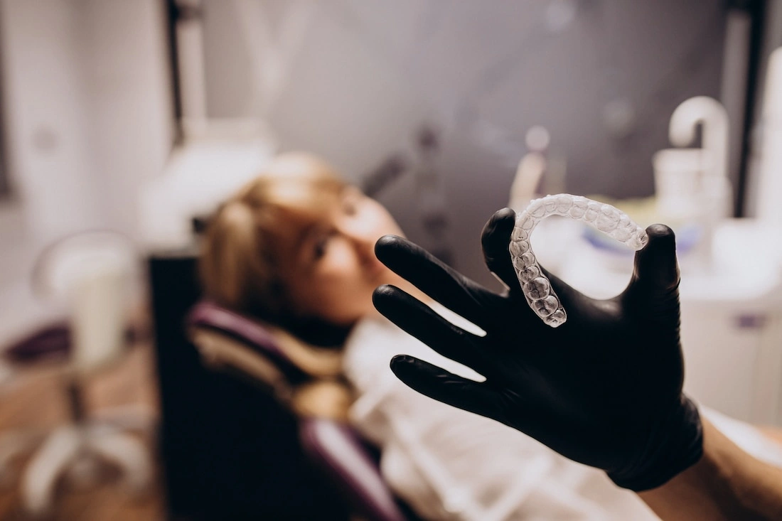 Orthodontist showing a clear plastic dental aligner for teeth straightening.